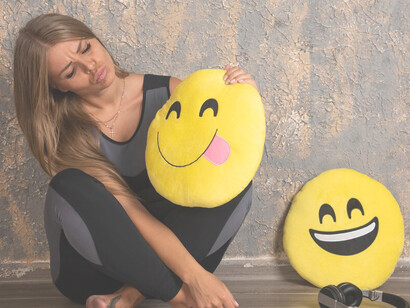 A sporty young girl, dressed in athletic gear, holding a smiling emoji pillow