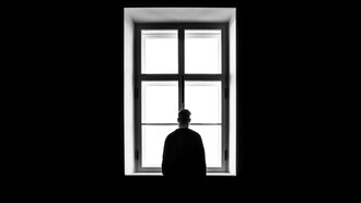 Homem contemplando janela. A demarcação emocional é uma metáfora que nos convida a explorar os territórios internos da mente