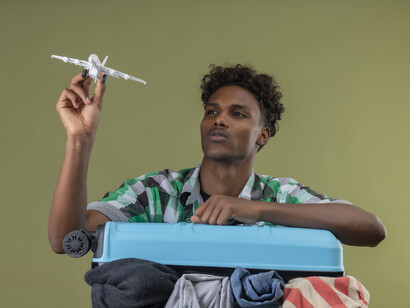 African American traveler preparing for an international trip with a suitcase, passport, and travel visa documents