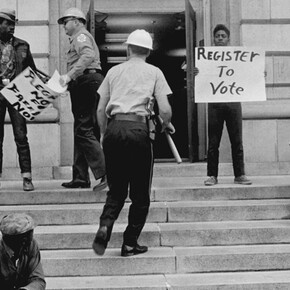 Sheriff Jim Clark arrests two demonstrators who displayed placards on the steps of the federal building in Selma, 1963. Gelatin silver print, 11 x 14 inches. © Danny Lyon, New York & Magnum Photos, New York / Courtesy Edwynn Houk Gallery, New York.