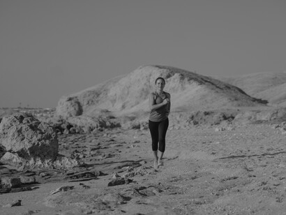 A woman jogging on the sandy beach listening to music