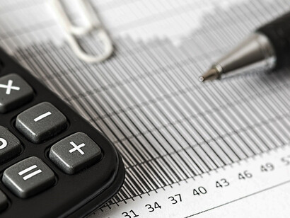In a focused and determined manner, a person uses a calculator to carefully calculate and plan their budget
