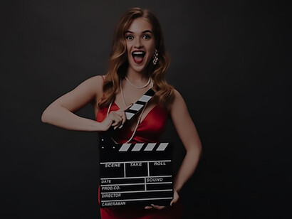 In the allure of a vibrant red dress, a chic woman strikes a captivating pose with a clapperboard in hand, set against the striking contrast of a black Hollywood star background