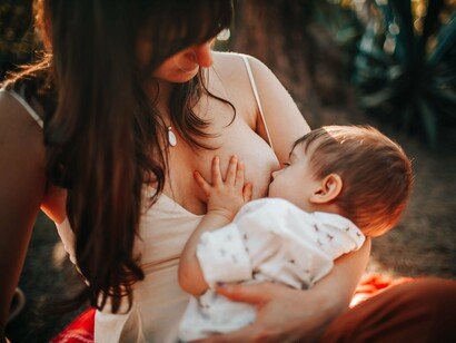 An infant breastfeeding while resting in the mother’s arms, symbolizing the complex nourishment and comfort provided by human milk