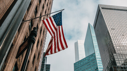 An American flag waves on the side of a brick building