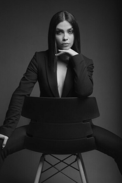 A woman sitting in a chair, dressed in a suit