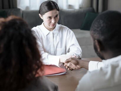 Uma profissional cumprimenta um homem durante uma reunião de atendimento, em um ambiente interno. A atuação do Serviço Social envolve escuta, compreensão das condições de vida e articulação de recursos que possam favorecer a reintegração à sociedade
