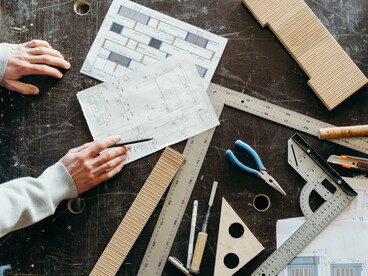 Hands examining construction plans across a drafting table, reflecting the importance of strategic preparation before large-scale growth