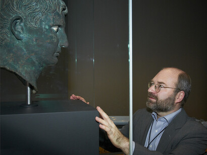 Curator of ‘The Meroë head of Augustus: Africa defies Rome’ Thorsten Opper facing the bronze Meroë head of Augustus in Room 3 at the British Museum © The Trustees of the British Museum