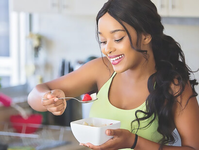 Radiant with joy, a woman sporting a cheerful smile as she prepares a delightful and health-conscious meal