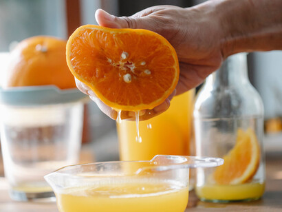 Laranja sendo expremida para liberar suas propriedades naturais em forma líquida