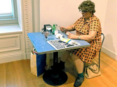 "Woman Eating" (1971) is a super-realistic sculpture of a woman sitting at a table eating by Duane Hanson