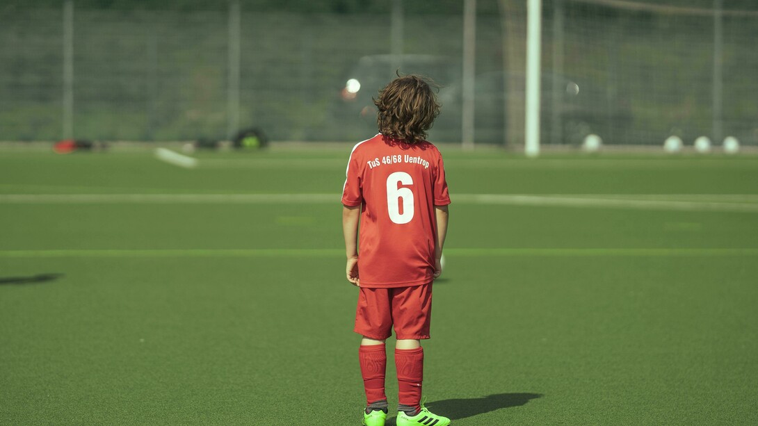“A faceless teenage football player standing on the field