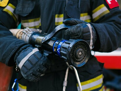 Profissional equipado com mangueira, aguardando ou se preparando para atuar. Representa a resposta que muitas vezes só acontece depois que o problema já começou
