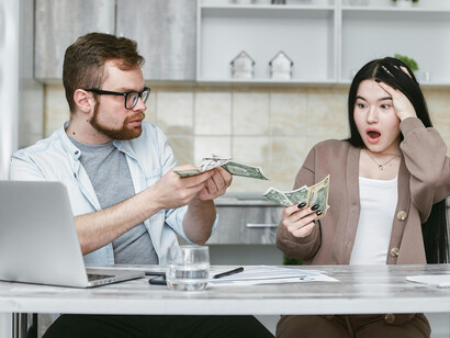 A man and woman working on their budget, reflecting financial anxiety and economic stress