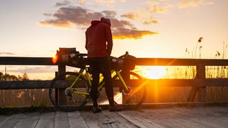 A bicycle traveler enjoying a peaceful sunset, representing low-carbon travel that connects people more closely with nature