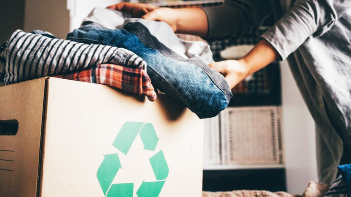 Mujer colocada su ropa usada en una caja de reciclaje para una 'segunda vida'