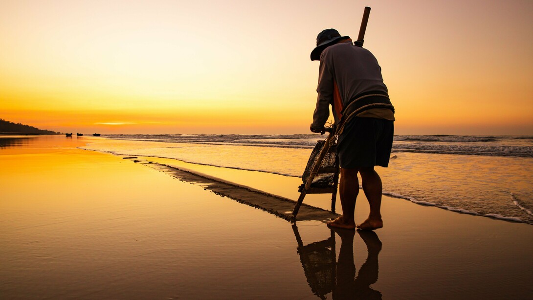 A solitary fisherman working along the water's edge at sunrise, symbolising the humble labour that replaced a future once imagined on the stage