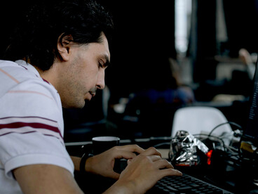 A programmer working at a desk on a laptop in a professional office environment