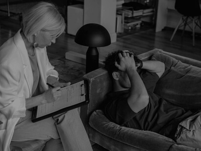 A man covers his face in frustration, faced with the questions of his therapist