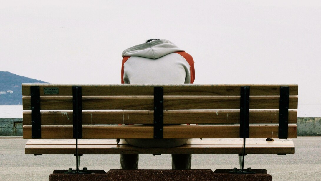Depressed man sits on a public bench