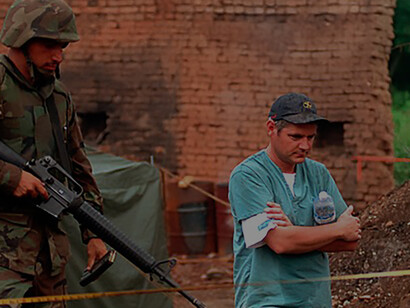 U.S. Marines secure a village in Kosovo as the Royal Canadian Mounted Police Forensics Team investigates a grave site on July 1, 1999, supporting NATO's Operation Joint Guardian for peacekeeping efforts