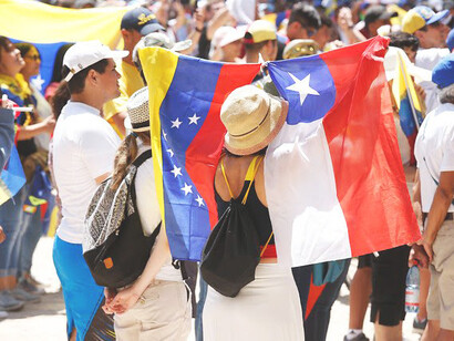 Una mujer y un hombre sostienen las banderas de Venezuela y Chile, en representación de la hermandad de dos naciones