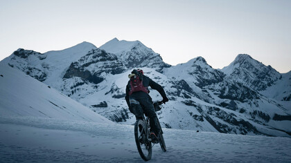 A cyclist riding through a snowy mountain trail, immersed in winter’s beauty, Nepal