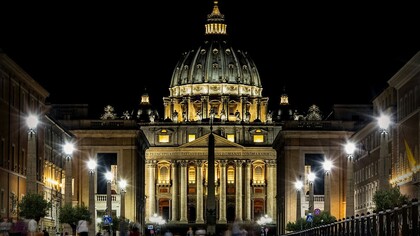 Spettacolare profilo della basilica di San Pietro illuminato dalle luci della sera, Roma, Italia. L'attuale basilica di San Pietro è frutto di più di due secoli di febbrili realizzazioni. L'obelisco che attualmente svetta maestoso al centro di Piazza San Pietro, il secondo per altezza a Roma, venne fatto trasportare dall' Egitto a Roma da Caligola