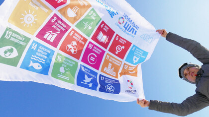 A woman holds a flag of the SDG of the UN