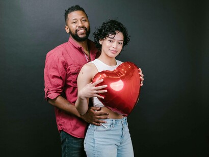 A couple smiling as they prepare to be intimate while holding a heart balloon