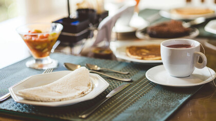Mesa de café da manhã brasileira com café coada, tapioca, salada de frutas e panqueca