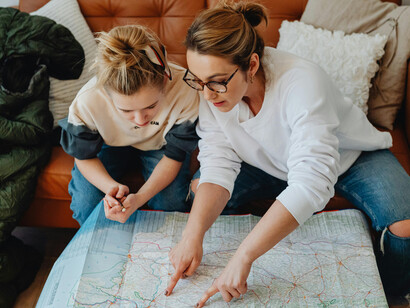 A woman pointing at a map with her daughter during a mindful travel planning moment