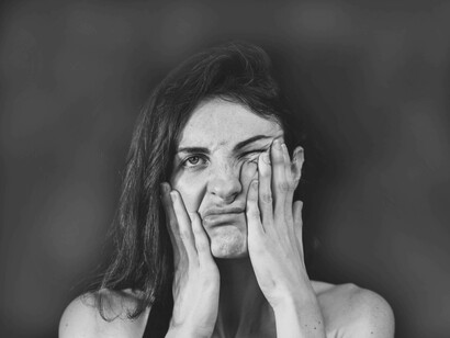 A young woman is trying to deal with her anxiety by rubbing her face