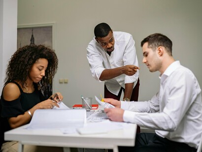 Employees reviewing documents in a tense office meeting, symbolizing the quiet suppression of disagreement within teams