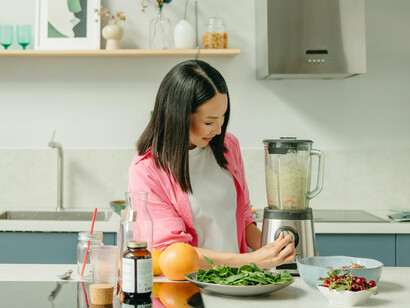 A woman blending fresh ingredients in the kitchen
