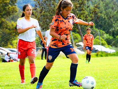 A girls’ football team immersed in the game, representing the innocence and excitement of grassroots sport