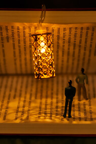 Miniature people and a lamp inside a half-open book
