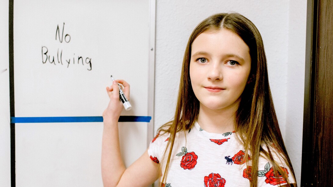 Menina escreve mensagem contra o bullying no quadro