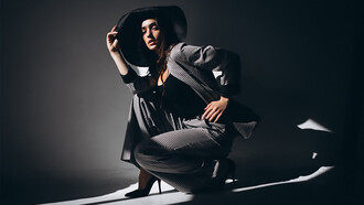 A woman in a business suit, accessorized with a hat