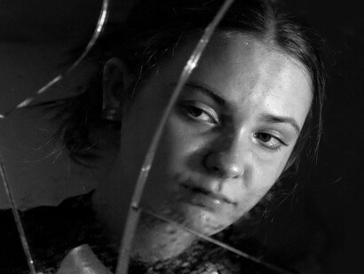 Mulher observa seu reflexo em espelho quebrado. A gratidão, nesse contexto, não é um sentimento passageiro, mas uma atitude consciente de reconhecimento. Ela desloca o foco do eu mereço para o eu recebi, criando uma mudança sutil e poderosa na forma como nos percebemos no mundo. Passamos a ver mais claramente os vínculos que nos sustentam e a desenvolver um senso maior de responsabilidade afetiva