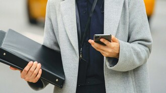 Mulher executiva utiliza o celular para trabalhar enquanto anda na rua