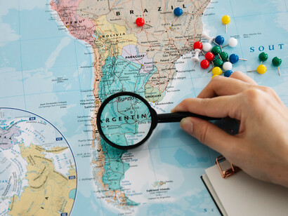 Una lupa revisa un mapa mundi. Las fuerzas que alteraron el destino y la historia de la humanidad han sido complejas y causado continuas emigraciones