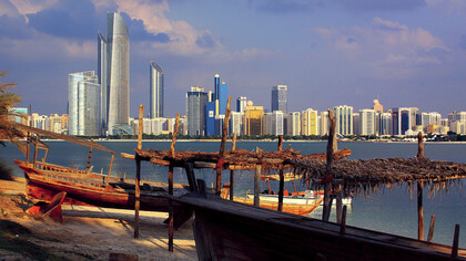 Skyline of Abu Dhabi, UAE, with boats moored at the shoreline 