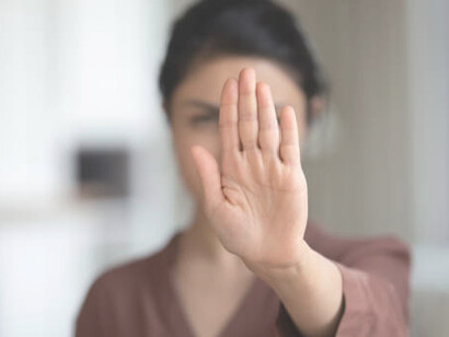 A shot of an unidentified woman gesturing the stop sign with her hand outdoors