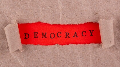 Illustrazione con etichetta "democrazia" scritta in rosso:" Abbiamo già assistito a una perdita dei valori democratici, dei capisaldi costituzionali, del modo di pensare collettivo che partiva dal presupposto di alcune regole di base condivise, fulcro del nostro modo di vivere, che hanno caratterizzato tutto il dopoguerra fino a qualche anno fa"