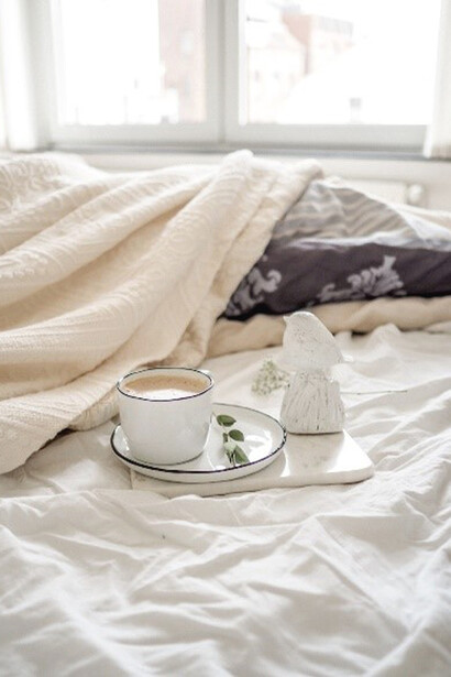 The presence of a steaming cup of coffee on the crisp white bed sheet added a touch of warmth, effortlessly transforming the space into a cozy haven