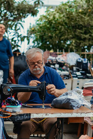 A man sitting at a table, with a gun beside him and a pile of laundry nearby, Turkey