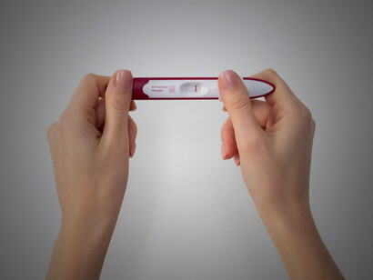A hand holding a negative pregnancy test, symbolizing the emotional toll of infertility