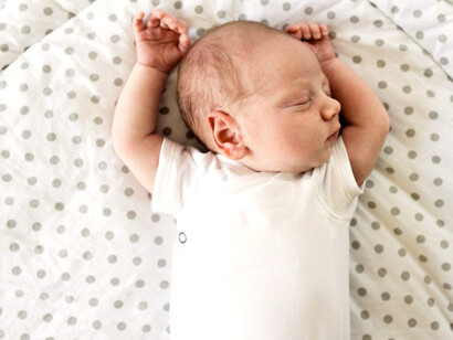 Recién nacido durmiendo con los brazos extendidos